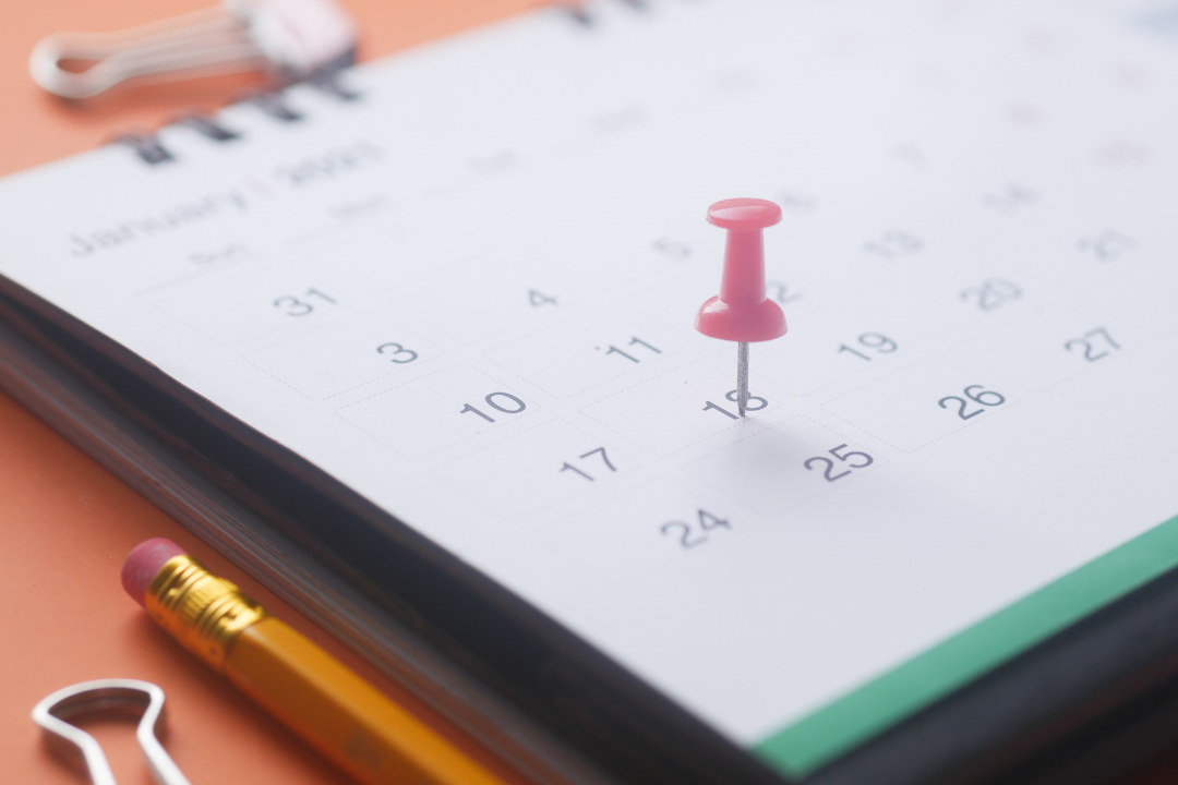 Close up image of a calendar with a pin placed on a date