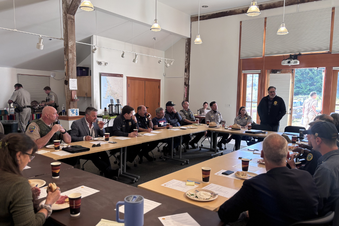 Firefighters, Sheriff and other law enforcement sitting around a table listening to speaker
