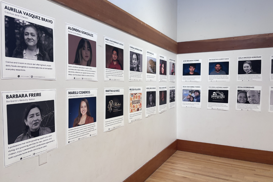 Photographs on a wall with business name captions below headshots of program graduates