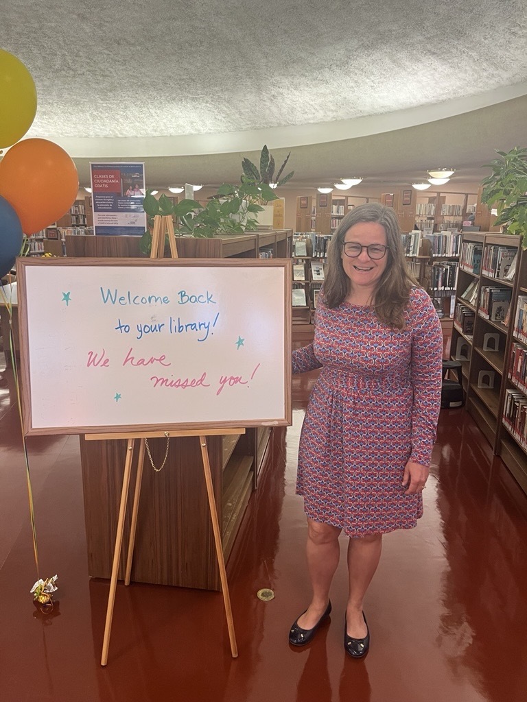 Mary next to welcome sign in Civic Center library