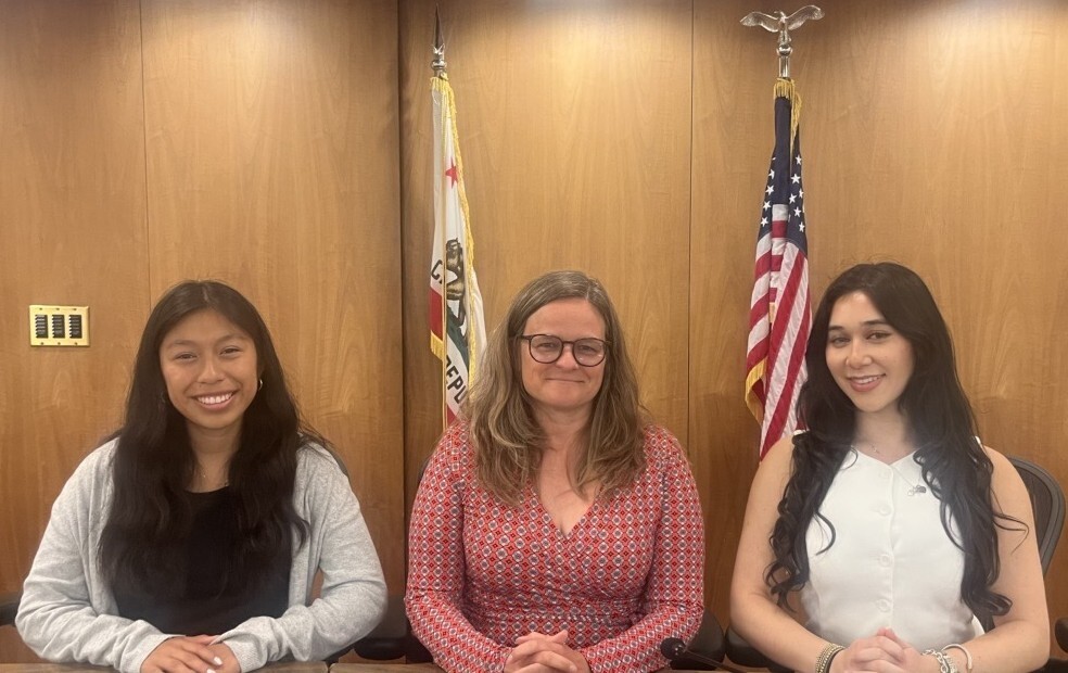 Interns Cate and Talia with Mary Sackett at Dais with flags in background
