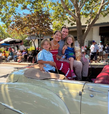 Eric and his family - wife and two kids - riding in a car in the Novato 4th of July Parade.