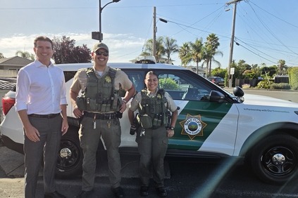Eric Luan in front of Sheriff vehicle with two sheriff officers