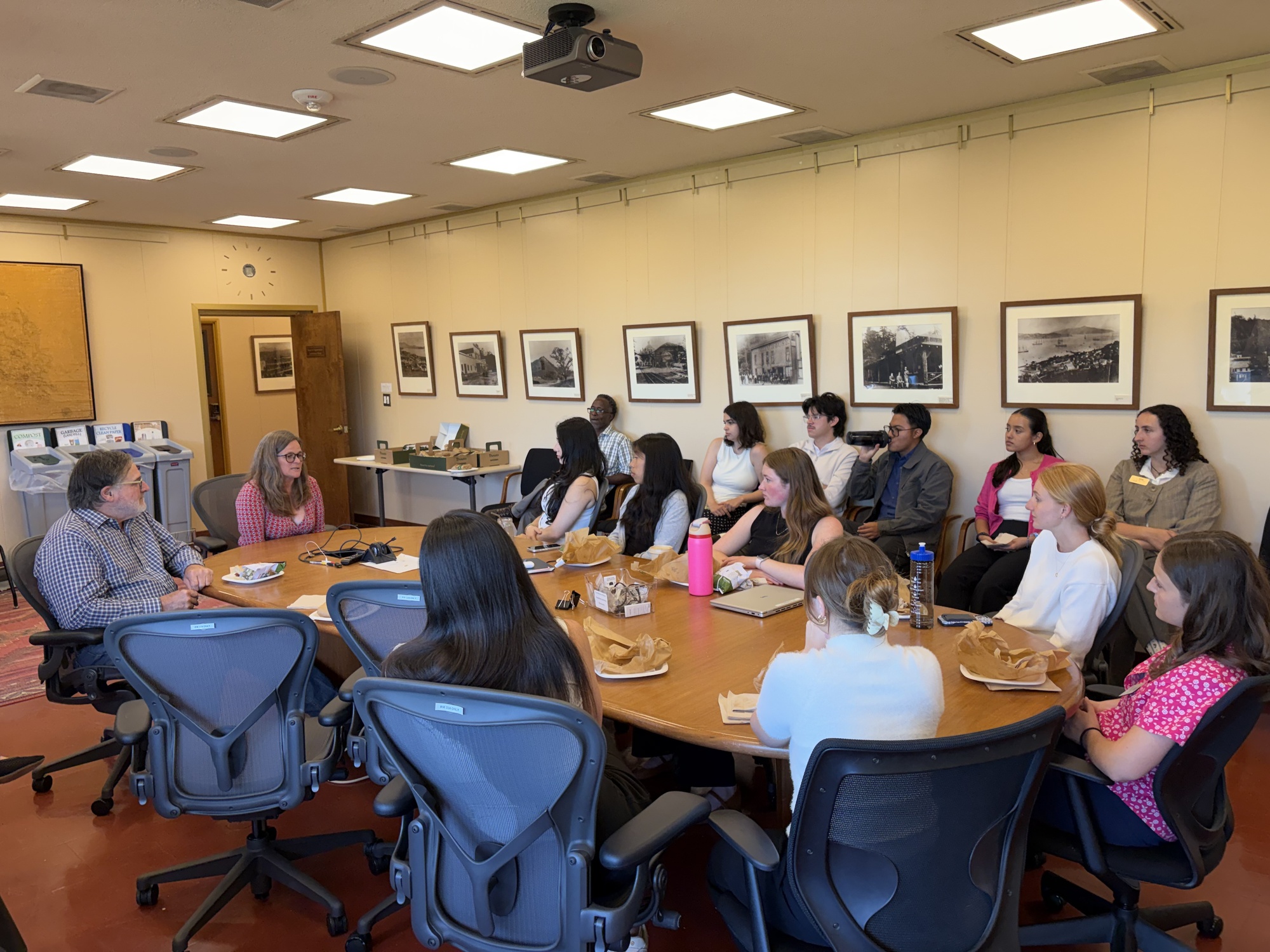 Mary and Dennis and interns seated around conference table in conversation