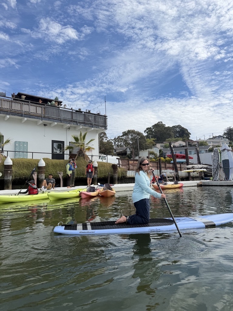 Mary on a paddleboard with other's getting in kayak in the background on the Canal