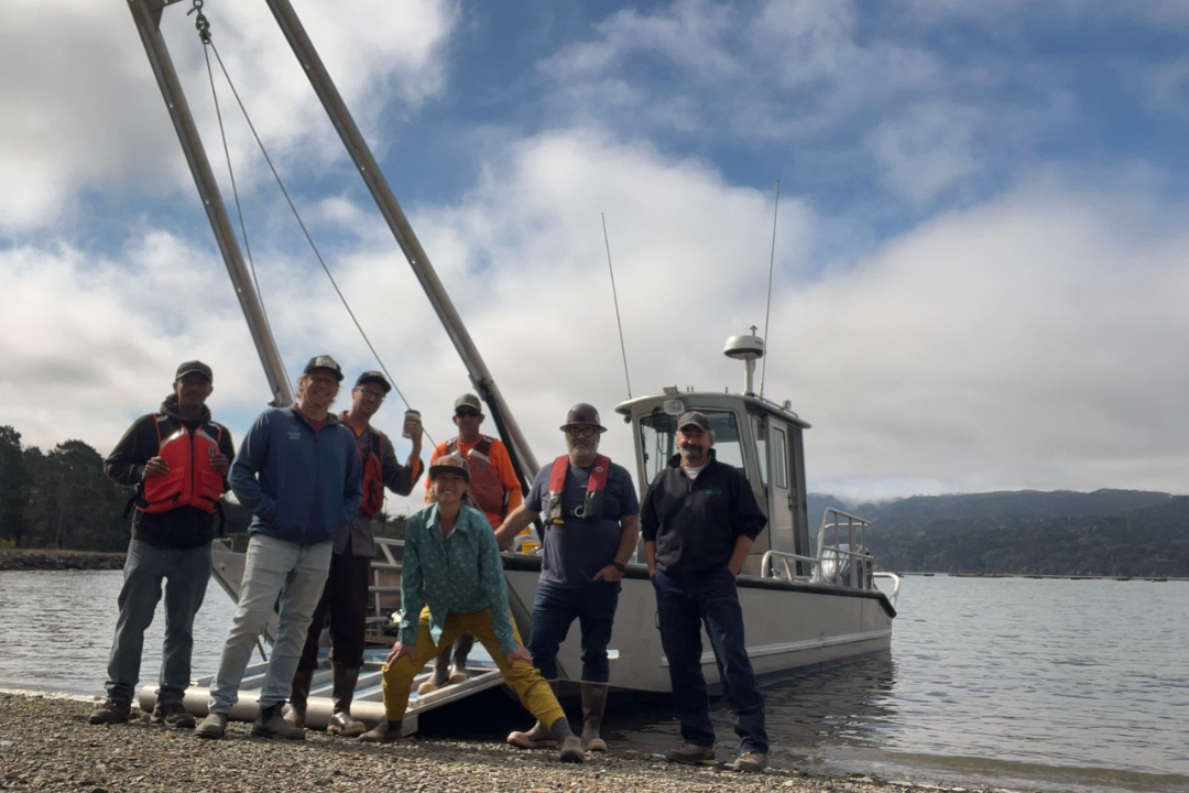 People standing in front of a boat along shoreline
