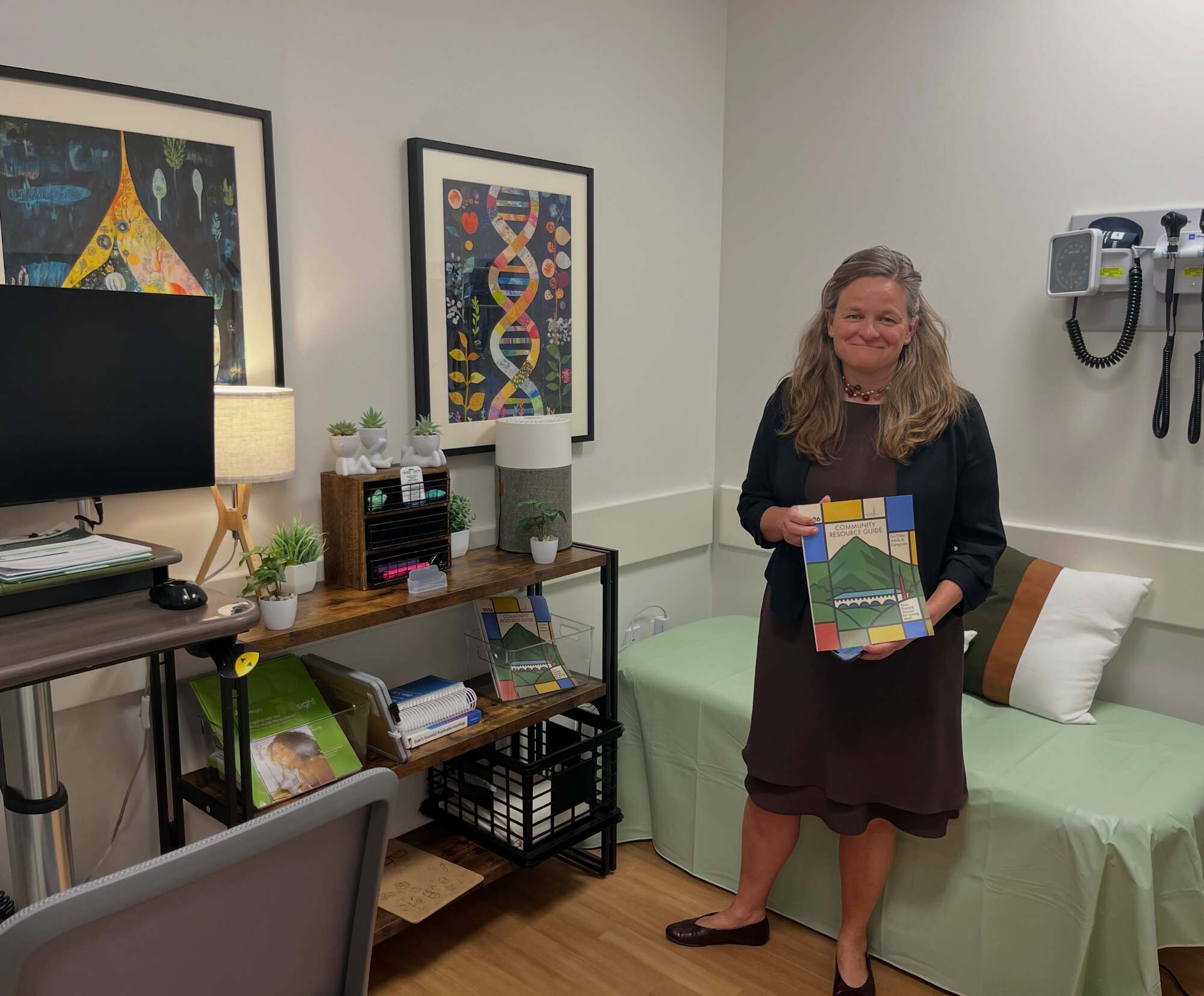 Mary holding the resource guide inside the warmly decorated Ritter Center exam room