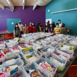 Teens standing behind kits packed to donate to the hospital.