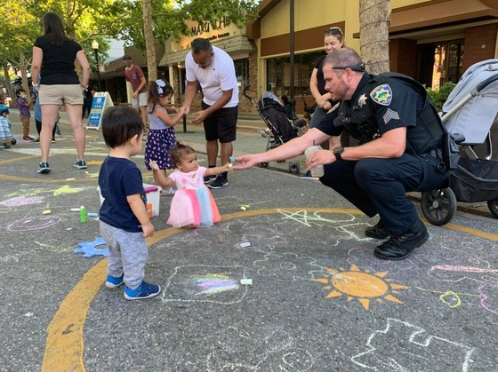 Image of Police Officer Handing Chalk to Child