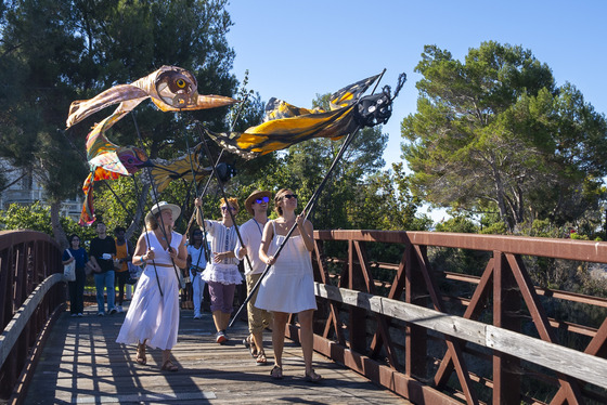 Volunteers holding kites in the shape of birds and insects