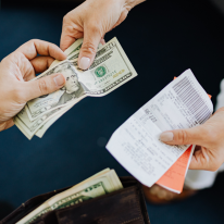 Two hands exchanging money and a receipt.