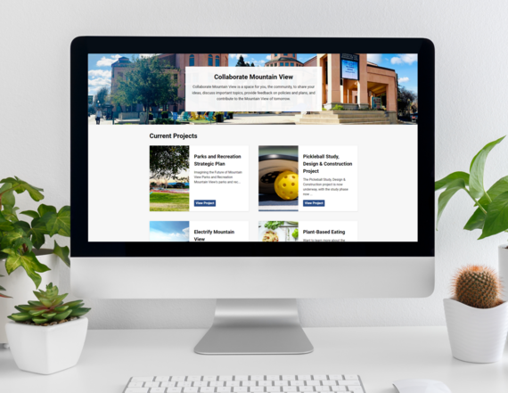 Collaborate Mountain View Landing Page on Computer Monitor with Plants on Left and Right Sides