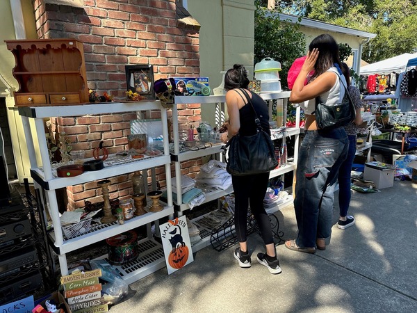 Two women looking at items for sale during Citywide Garage Sale