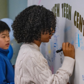 Teen writing on a mural