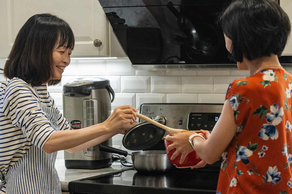 Woman serving friend food cooked on electric induction stove