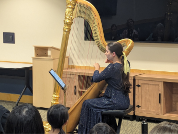 Photo of harpist Aysha Gomez-Kureishi playing the harp in front of an audience