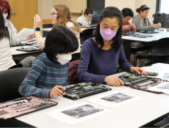 Photo of a parent and child working on dissembling Thinkpad laptops