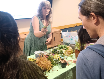 Photo of Master Gardener Laura Westley at a table with succulent cuttings as attendees look on