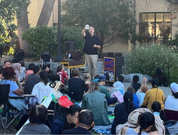 Photo of Mike the Magician showing a magic trick to a large audience in Pioneer Park