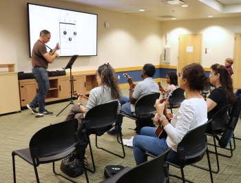 Photo of ukulele instructor Chuck Monahan showing attendees how to play a chord
