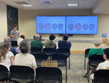 Photo of a teen presenting on ancient coinage to an audience