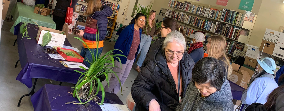 Photo of Plant Exchange attendees looking at plants on tables in the bookmobile garage