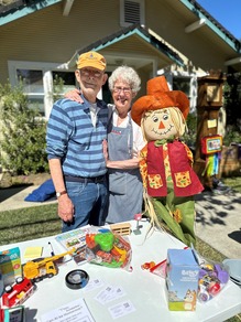 Two people standing next to  scarecrow selling items