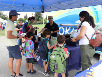 Photo of library staff talking with table visitors at MVWSD's Back to School Event