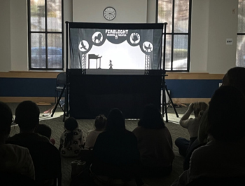 Photo of a shadow puppet performance in front of a crowd