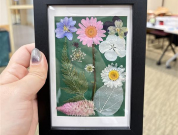 Photo of a decorative photo frame with pressed flowers and leaves inside