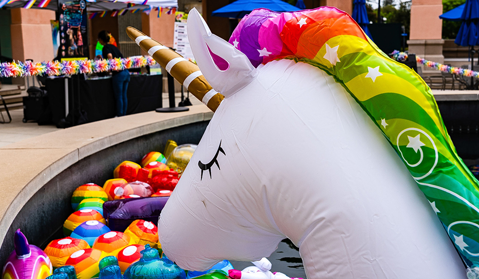A picture of a blowup white unicorn with a rainbow-colored mane and a stiped horn