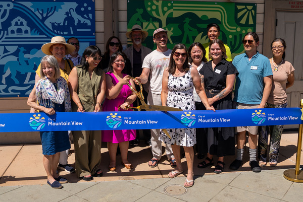 Picture of people standing in front of artwork at the transit center cutting a blue ribbon