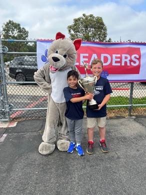 Photo of mascot and winners holding trophy