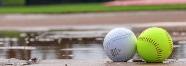 Photo of a baseball and softball sitting in a mud puddle
