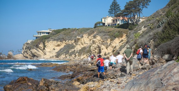 View of ocean and cliffs with children and guides exploring the tidepools