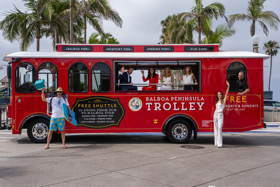 City Council stand in front of the new, red Balboa Peninsula Trolley in front of Balboa Pier. 