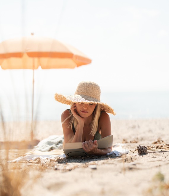 woman reading book on the beach