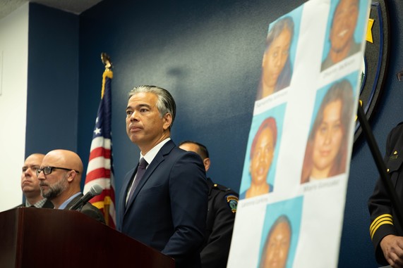 Image of Attorney General near poster of suspects 