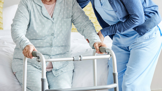 Image: Woman with walker being assisted by care worker