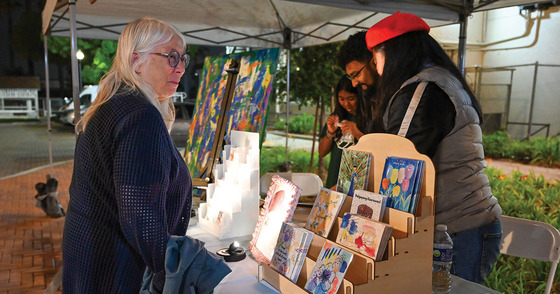 Artist vendor in her booth with a woman shopping