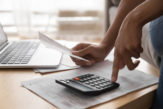 image of someone using a calculator and holding a bill