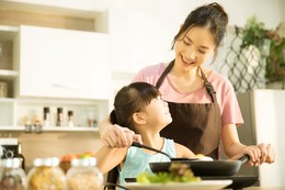 Mother and daughter cooking on portable induction cooktop