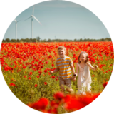 Kids in flower field with wind turbine in background