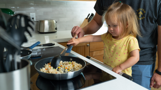 child cooking on an induction cooktop with supervision