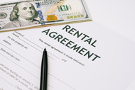 Photo of a one hundred dollar bill and a pen laying on top of a rental agreement. 