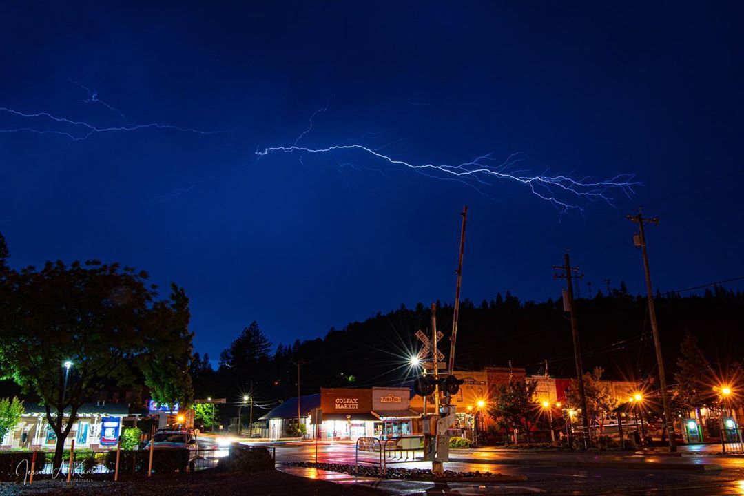 Photo of downtown Colfax at night with lighting in the sky./