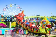 Photo of people riding a small roller coaster at a fair. 