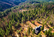 Daytime aerial photo of a home on a forested hill