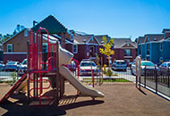 A children't outdoor playground surrounded by a colorful new apartment complex