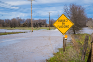 Subject to flooding sign next to a flooded road